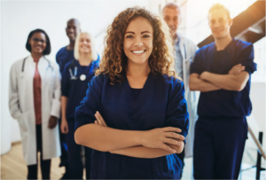 Photo of a group of six medical professionals smiling. A female with her arms crossed stands in the front of the group.