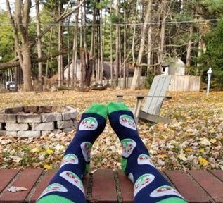 An Orchard employee is showing off their new Orchard socks while sitting outside.