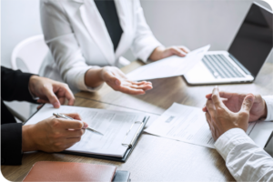Photo of three medical professionals sitting around a table and looking over documents.