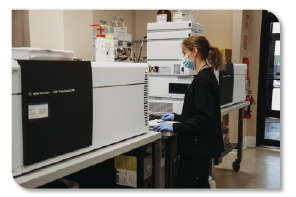 Photo of a lab technician standing next to a testing machine